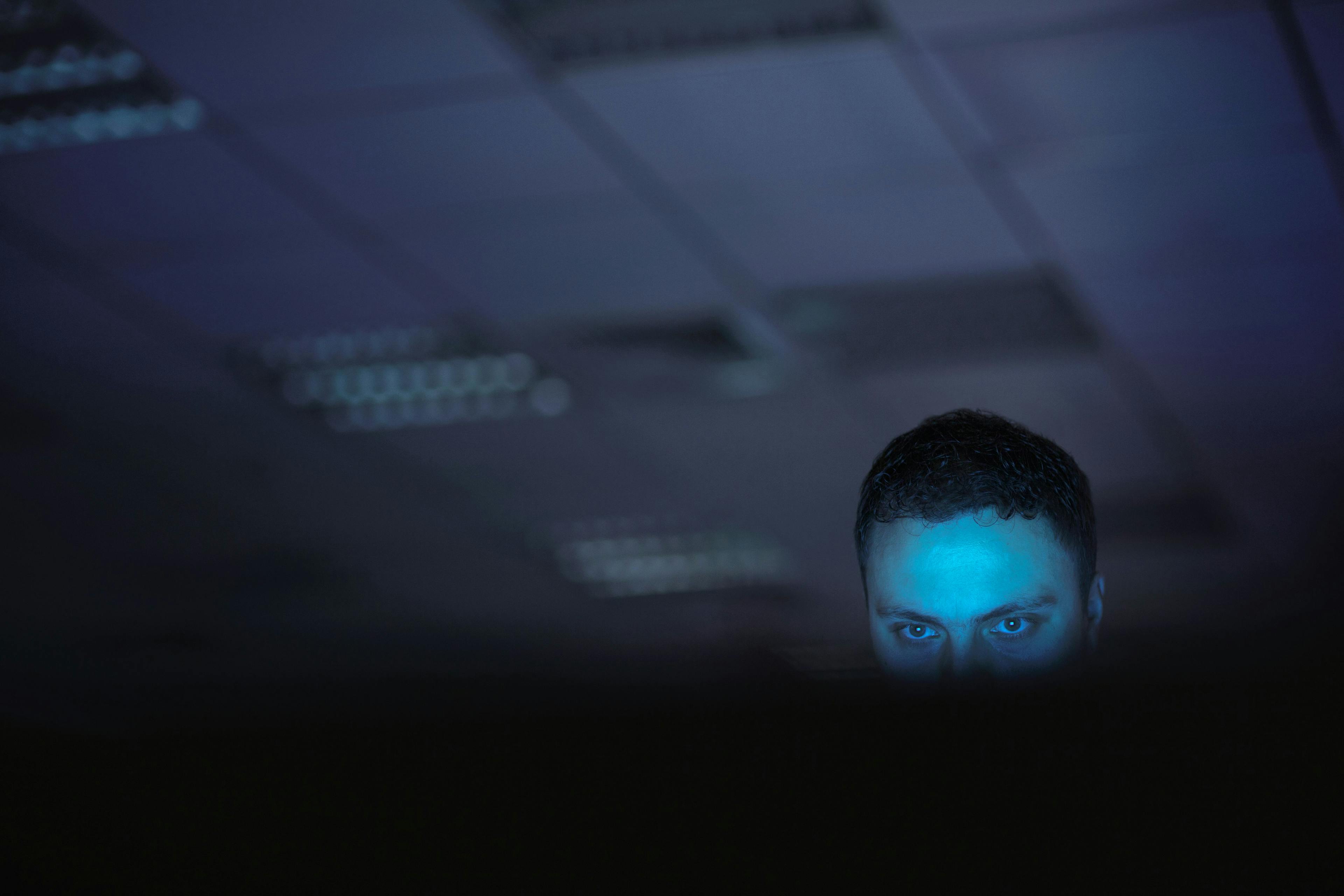 A person uses a computer in a darkened office.
