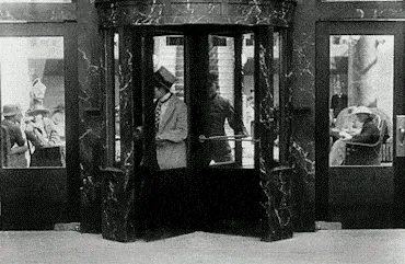 Charlie Chaplin goes through a revolving door.